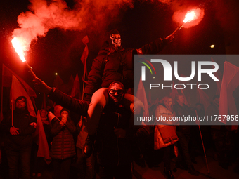 People hold lit flares as they take part in the 106th anniversary of Poland regaining its independence in Warsaw, Poland, on November 11, 20...