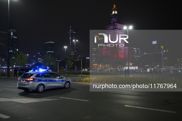 Police block the main road before the Palace of Culture and Science, which is lit in the colors of Poland's national flag during the 106th a...