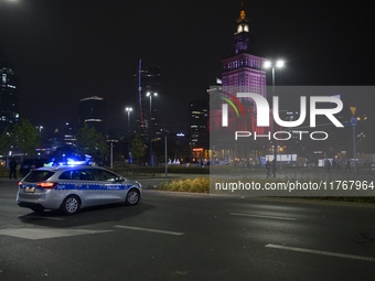 Police block the main road before the Palace of Culture and Science, which is lit in the colors of Poland's national flag during the 106th a...