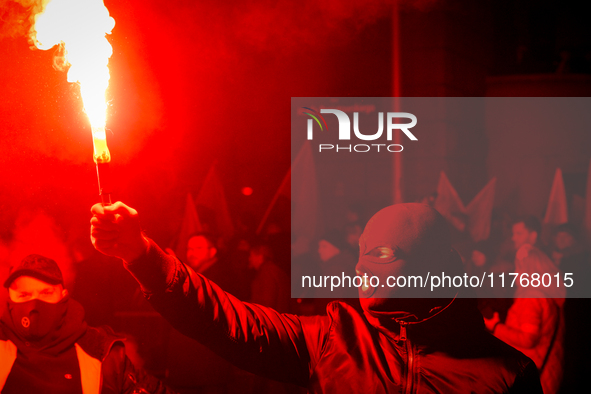 An Independence Day march participant wearing a balaclava lights a flare in Warsaw, Poland on 11 November, 2024. A march organized by far-ri...