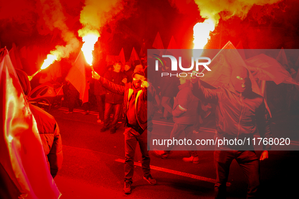 Participants light flares while threatening a journalist in Warsaw, Poland on 11 November, 2024. A march organized by far-right, nationalist...