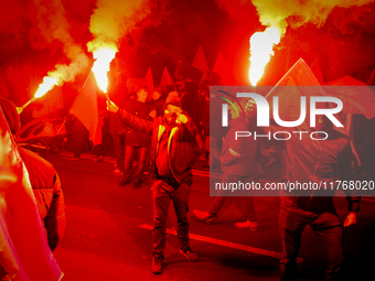 Participants light flares while threatening a journalist in Warsaw, Poland on 11 November, 2024. A march organized by far-right, nationalist...