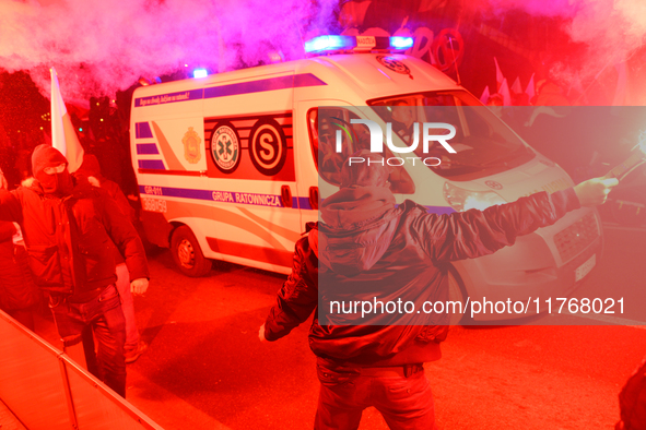 Paricipants light flares as an ambulance passes through the Independence Day march in Warsaw, Poland on 11 November, 2024. A march organized...