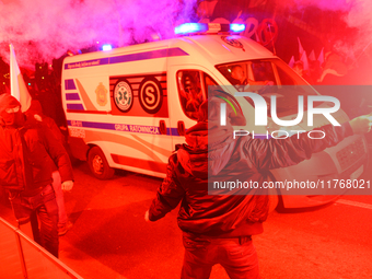 Paricipants light flares as an ambulance passes through the Independence Day march in Warsaw, Poland on 11 November, 2024. A march organized...