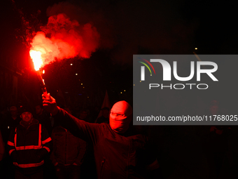 A man wearing a balaclava lights a flare in Warsaw, Poland on 11 November, 2024. A march organized by far-right, nationalist organizations w...