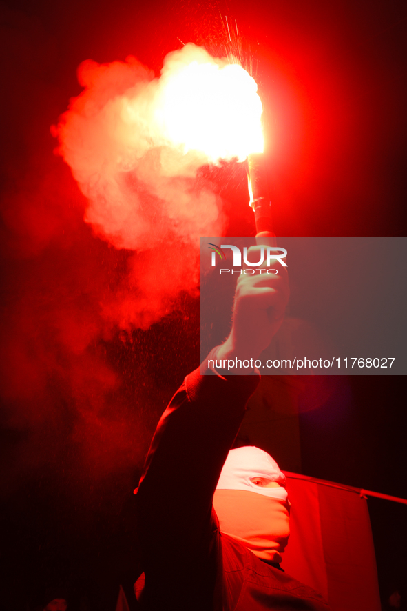 A man wearing a balaclava lights a flare in Warsaw, Poland on 11 November, 2024. A march organized by far-right, nationalist organizations w...