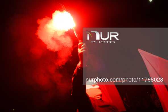 A man wearing a balaclava lights a flare in Warsaw, Poland on 11 November, 2024. A march organized by far-right, nationalist organizations w...