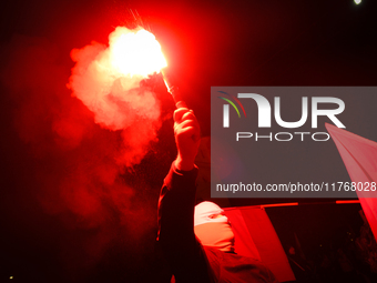 A man wearing a balaclava lights a flare in Warsaw, Poland on 11 November, 2024. A march organized by far-right, nationalist organizations w...