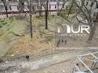 People stand among broken tree branches outside a hostel where internally displaced persons live, which is damaged by an overnight Russian a...