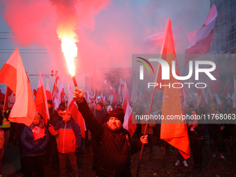 A man lights a flare during inedpendence day celebrations in Warsaw, Poland on 11 November, 2024. A march organized by far-right, nationalis...