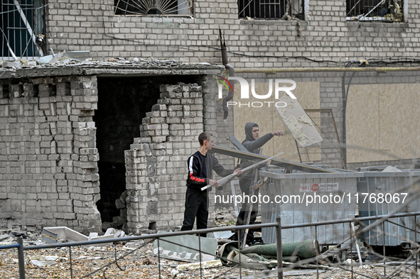 In Zaporizhzhia, Ukraine, on November 11, 2024, men throw debris into garbage containers outside a hostel where internally displaced persons...