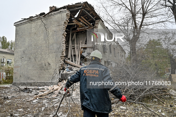 A rescuer picks up branches torn down by a shock wave outside an apartment block where a child is injured after an overnight Russian air str...