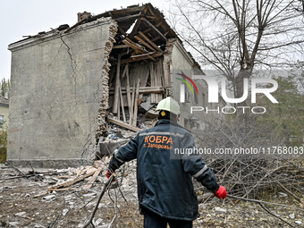 A rescuer picks up branches torn down by a shock wave outside an apartment block where a child is injured after an overnight Russian air str...