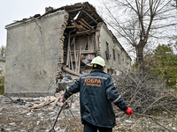 A rescuer picks up branches torn down by a shock wave outside an apartment block where a child is injured after an overnight Russian air str...