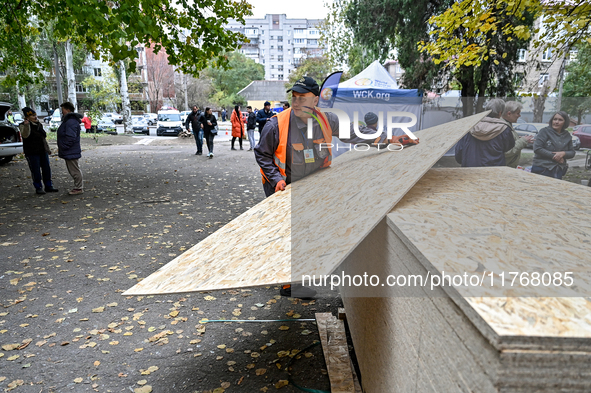 A volunteer picks up an OSB to seal a window knocked out by a shock wave outside a hostel where internally displaced persons live, damaged b...