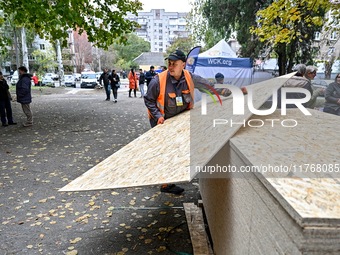 A volunteer picks up an OSB to seal a window knocked out by a shock wave outside a hostel where internally displaced persons live, damaged b...