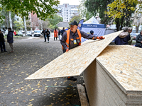 A volunteer picks up an OSB to seal a window knocked out by a shock wave outside a hostel where internally displaced persons live, damaged b...