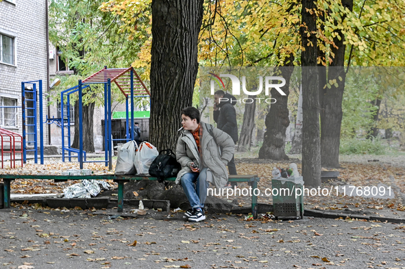 A woman with belongings sits on a bench outside a hostel where internally displaced persons live, which is damaged by an overnight Russian a...