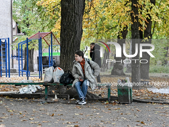 A woman with belongings sits on a bench outside a hostel where internally displaced persons live, which is damaged by an overnight Russian a...