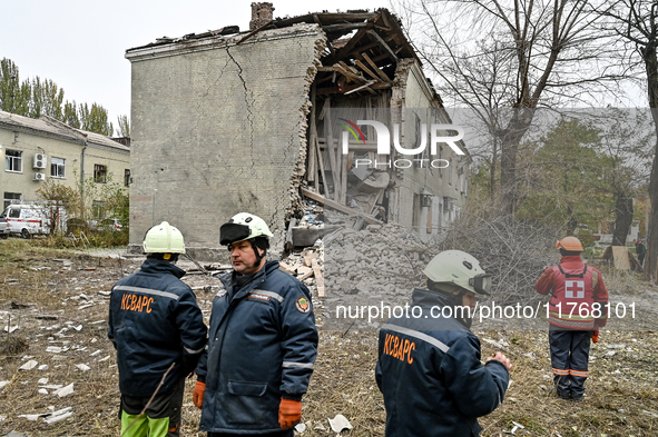 Rescuers and volunteers stand outside an apartment block where a child is injured after an overnight Russian air strike in Zaporizhzhia, Ukr...