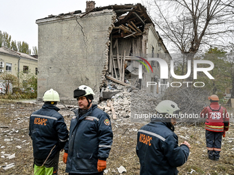 Rescuers and volunteers stand outside an apartment block where a child is injured after an overnight Russian air strike in Zaporizhzhia, Ukr...