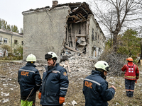 Rescuers and volunteers stand outside an apartment block where a child is injured after an overnight Russian air strike in Zaporizhzhia, Ukr...