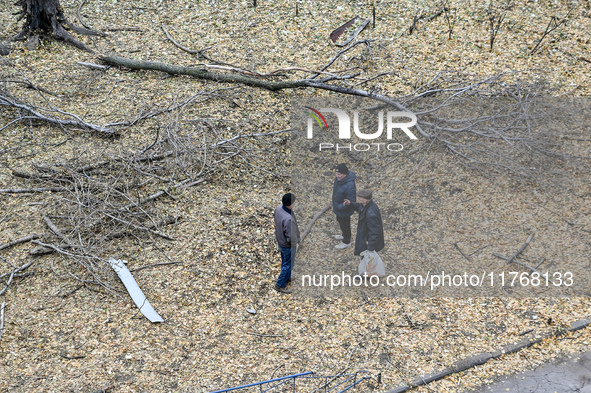 Three men talk among broken tree branches outside a hostel where internally displaced persons live that is damaged by an overnight Russian a...