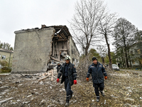 Rescuers pick up branches brought down by a shock wave outside an apartment block where a child is injured after an overnight Russian air st...