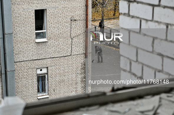 A man sweeps away glass shards with a broomstick in the yard of the sports complex of the Zaporizhzhia Polytechnic National University, whic...