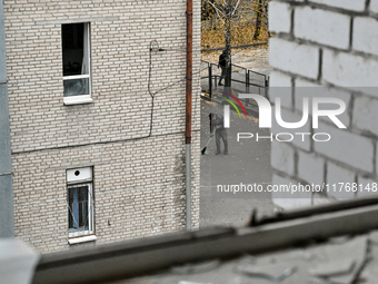 A man sweeps away glass shards with a broomstick in the yard of the sports complex of the Zaporizhzhia Polytechnic National University, whic...