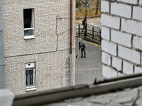 A man sweeps away glass shards with a broomstick in the yard of the sports complex of the Zaporizhzhia Polytechnic National University, whic...