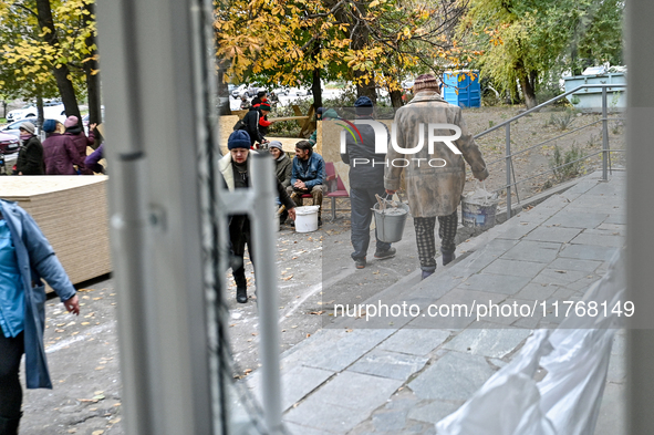 Residents stand outside a hostel where internally displaced persons live, which is damaged by an overnight Russian air strike in Zaporizhzhi...