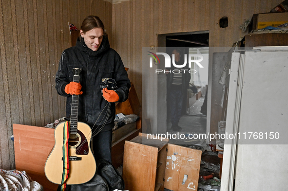 A man holds a broken guitar in a room of a hostel where internally displaced persons live, damaged by an overnight Russian air strike in Zap...