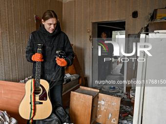 A man holds a broken guitar in a room of a hostel where internally displaced persons live, damaged by an overnight Russian air strike in Zap...