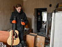 A man holds a broken guitar in a room of a hostel where internally displaced persons live, damaged by an overnight Russian air strike in Zap...