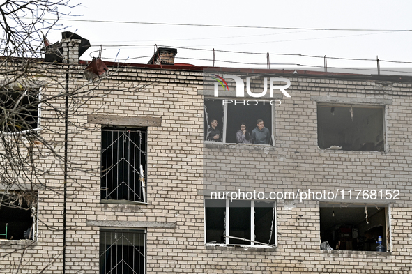 People look out of a window knocked out by a shock wave in a room of a hostel where internally displaced persons live, damaged by an overnig...