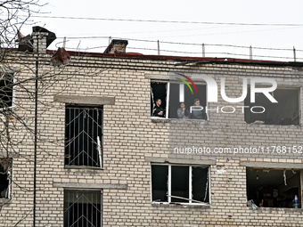 People look out of a window knocked out by a shock wave in a room of a hostel where internally displaced persons live, damaged by an overnig...