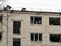 People look out of a window knocked out by a shock wave in a room of a hostel where internally displaced persons live, damaged by an overnig...