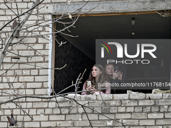 Two women look out of a window knocked out by a shock wave in a room of a hostel where internally displaced persons live, damaged by an over...