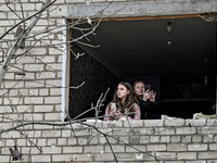 Two women look out of a window knocked out by a shock wave in a room of a hostel where internally displaced persons live, damaged by an over...