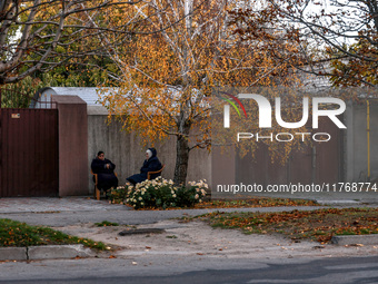 Women sit in plastic chairs in the street by the fence in Kherson, Ukraine, on November 7, 2024. (