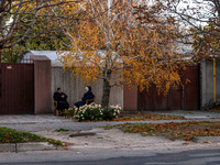 Women sit in plastic chairs in the street by the fence in Kherson, Ukraine, on November 7, 2024. (