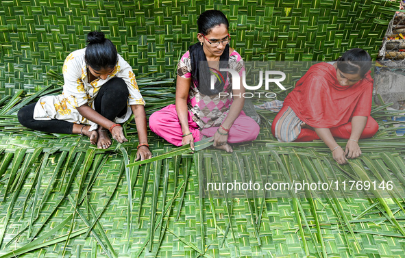 Women weave coconut leaves to prepare a traditional decorative background for the upcoming wedding season at a street side in Hyderabad, Ind...