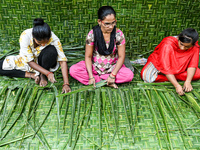 Women weave coconut leaves to prepare a traditional decorative background for the upcoming wedding season at a street side in Hyderabad, Ind...