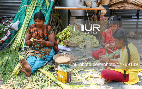 A woman with her daughters weaves coconut leaves into different shapes used for traditional wedding decorations for the upcoming wedding sea...