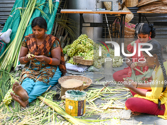 A woman with her daughters weaves coconut leaves into different shapes used for traditional wedding decorations for the upcoming wedding sea...