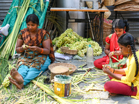 A woman with her daughters weaves coconut leaves into different shapes used for traditional wedding decorations for the upcoming wedding sea...