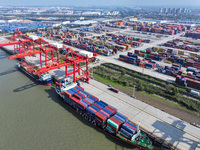 Cargo ships load and unload at berths, and trucks shuttle in the yard at Longtan Port area of Nanjing Port in Nanjing, Jiangsu province, Chi...