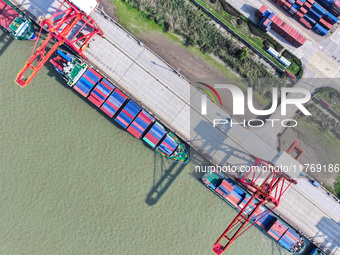 Cargo ships load and unload at berths, and trucks shuttle in the yard at Longtan Port area of Nanjing Port in Nanjing, Jiangsu province, Chi...