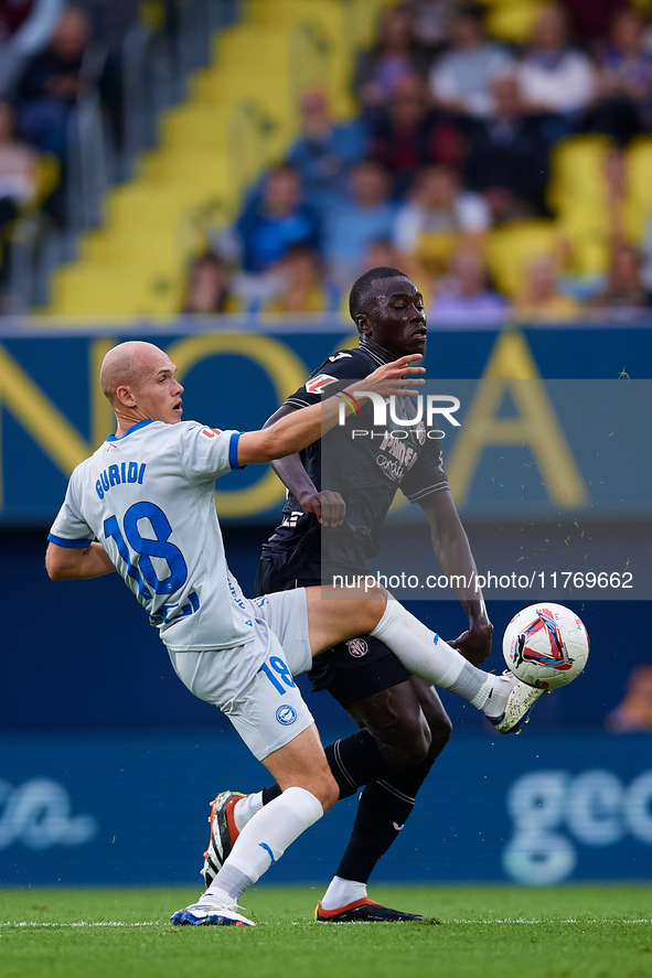 Jon Guridi of Deportivo Alaves competes for the ball with Gueye of Villarreal CF during the LaLiga EA Sports match between Villarreal CF and...